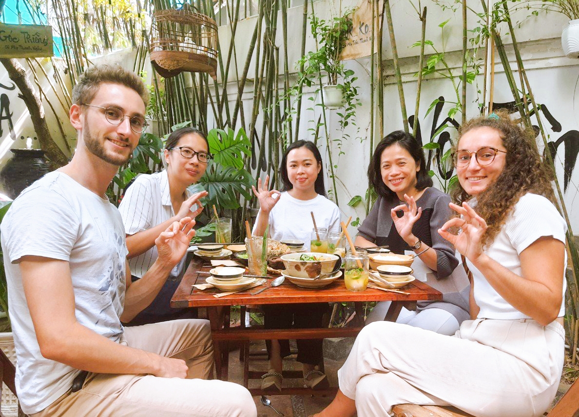 International diners smiling while tasting fresh plant-based Vietnamese dishes in Saigon