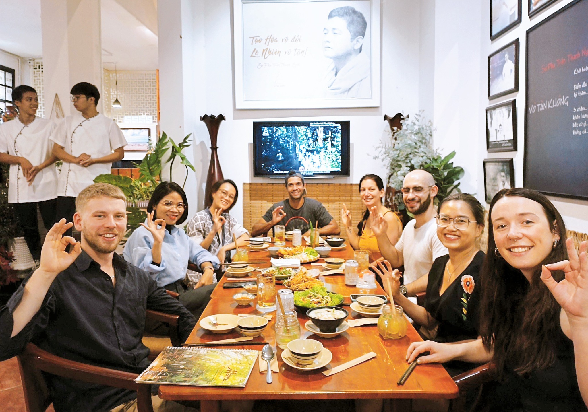 International diners smiling while sharing a healthy vegetarian meal in Saigon