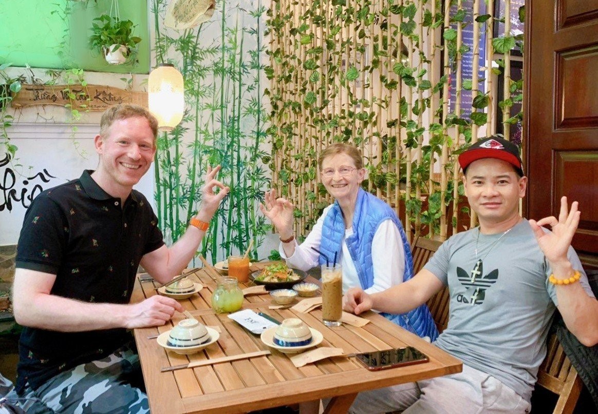 International diners smiling and enjoying traditional plant-based Vietnamese cuisine