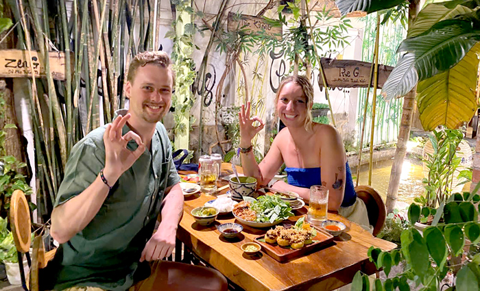 Smiling foreign visitors enjoying healthy vegetarian dishes in central Saigon.